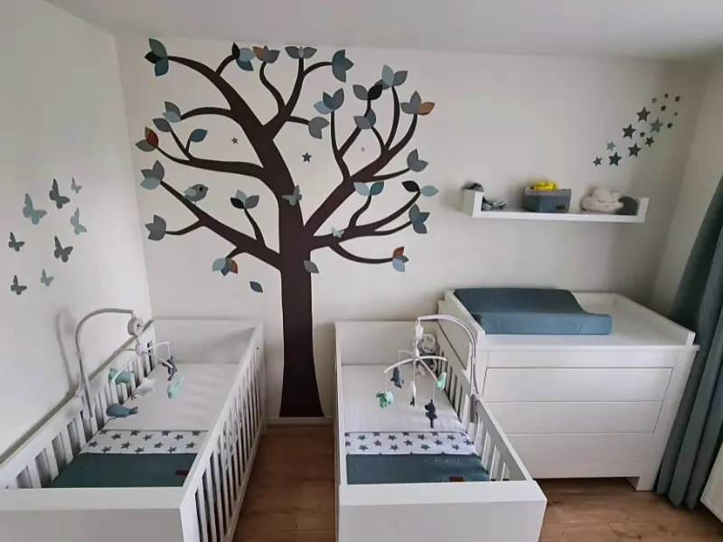 Neutrale tweeling babykamer in groen en wit met een behangboom als muurdecoratie